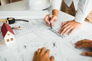 Architects engineer working with blueprints on table and discussing project together at the meeting in the office. photo