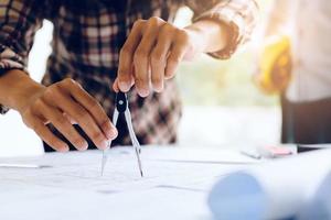 Engineering man working on blueprint in workplace and drawing compass. photo