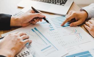 Two businessmen are pointing to the company sales graph paper and then analyzing together. photo
