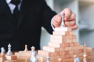 Businessman hand picking chess on top block wood about leadership concept. photo