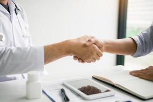 Doctor shaking hands with older patient in the clinic room. photo