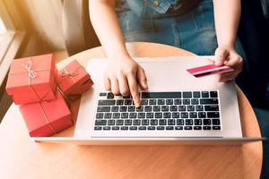 Top view of woman hand holding credit card and doing shopping online near window at home. photo