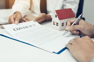 Young asian man signing on paper financial contract with real estate agent. photo