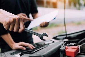 el mecánico de automóviles sostiene una llave lista para revisar el motor y el mantenimiento. foto