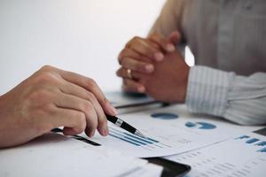 Two business partnership coworkers analysis cost work progress and gesturing with discussing a financial planning graph and company financial during a budget meeting in office room. photo