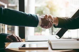 Entrepreneurs collaboration deal shaking hands in a modern office and financial paper graph on desk. photo