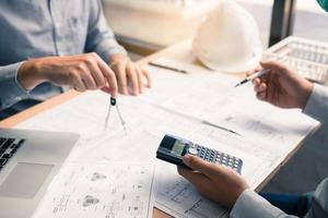 Architect working on blueprint in workplace with partnership and drawing compass. photo