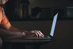 Man typing on keyboard and working at computer laptop in night. photo