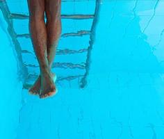 adult African American man's legs underwater in swimming pool photo