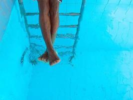 Las piernas de un hombre afroamericano adulto bajo el agua en la piscina foto