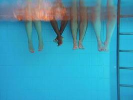 piernas de hombre afroamericano con amigos caucásicos en piscina bajo el agua. verano. concepto de vacaciones, internacional y deportivo. foto