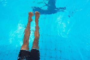 piernas de persona de natación caucásica y escaleras en piscina bajo el agua. abstracto. fiesta. verano. concepto de vacaciones y deporte. foto