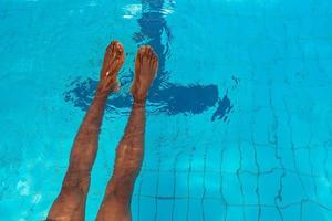 Las piernas de un hombre afroamericano adulto bajo el agua en la piscina foto