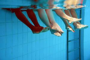 Legs of African American man with caucasian friends in swimming pool underwater. Summer. Vacation, international and sport concept. photo