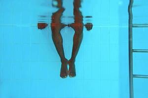 adult African American man's legs underwater in swimming pool photo