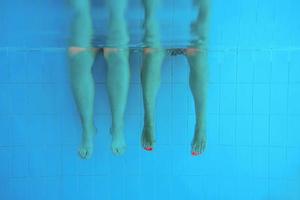 piernas de dos personas bajo el agua en la piscina. fiesta. verano. concepto de vacaciones, diversidad, amistad y deporte. foto