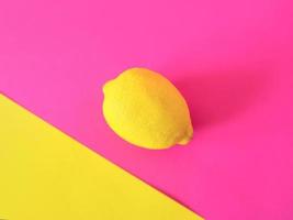 stylish yellow lemon on pink and yellow background. Citrus, summer, fruits concept photo