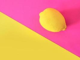 stylish yellow lemon on pink and yellow background. Citrus, summer, fruits concept photo