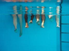 Legs of African American man with caucasian friends in swimming pool underwater. Summer. Vacation, international and sport concept. photo