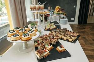 pasteles dulces con bayas y pasteles y otros postres en la mesa del banquete foto