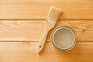 Brush with a jar of paint on a background of natural wooden boards photo