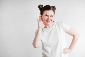 Portrait of beautifull woman raised her palm to her ear in a listening gesture on a white background. Copy, empty space photo