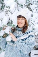 retrato de invierno de una mujer hermosa cerca de los árboles cubiertos de nieve foto