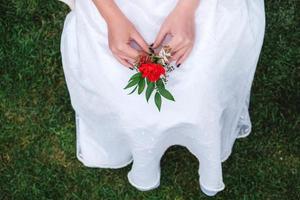 Boutonniere for wedding in the hands of a girl bride in a white dress. Copy, empty space for text photo