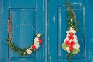 corona decorada de flores, hojas y hierba seca sobre un fondo de puerta azul de madera. copiar, espacio vacío para texto foto
