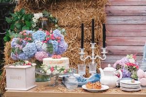 Wedding candy bar in rustic style decorated with plates, cutlery, glasses, candles and flower arrangements. Copy, empty space for text photo