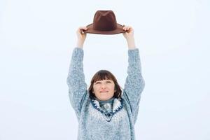 Woman in a brown hat and sweater on a background of snow-covered forest photo