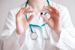 Woman doctor with pills in her hands on a white background. Taking vitamins or medications. Copy, empty space for text photo