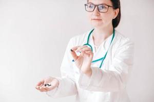 Beautiful woman doctor with pills in her hands on a white background. Taking vitamins or medications. Copy, empty space for text photo