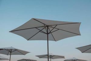 White beach umbrellas on sky background. Copy, empty space for text photo