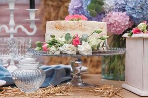 White wedding cake decorated by flowers standing of festive table. Copy, empty space for text photo