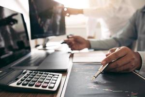 Close up of pen investors are working together with analyzing the stock data graphs in the paper and viewing the data on the laptop screen. photo