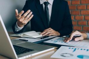 Discusión del equipo de negocios sobre la compañía de costos financieros trabajando juntos y señalando el gráfico de resumen en papel. foto