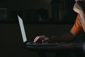 Man typing on keyboard and working at computer laptop in night. photo