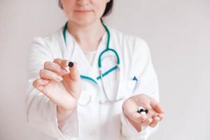 Woman doctor with pills in her hands on a white background. Taking vitamins or medications. Copy, empty space for text photo