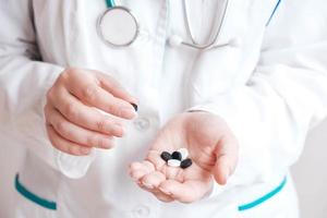 Woman doctor with pills in her hands on a white background. Taking vitamins or medications. Copy, empty space for text photo