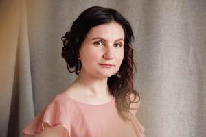 Portrait brunette woman in a pink dress on a background of linen fabric. Copy, empty space for text photo