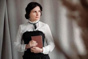 Portrait of a woman in vintage style dressed holding a book in his hands on a background of linen cloth photo