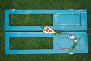 Decorated wreath of flowers, leaves and dry grass on a wooden blue door background. Copy, empty space for text photo