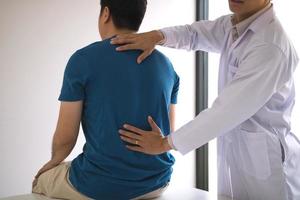 Physical therapists are using hands to check the back of the patient. photo