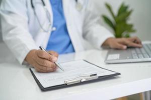 médico escribir nota médica de salud en el portapapeles con la computadora portátil en el hospital. foto