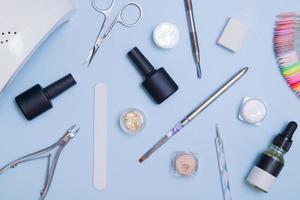 Top view of tools and materials for modern manicure and nail extension. Knolling on blue background. Flat lay manicure tools photo