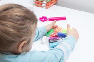 The girl at the table is playing with modeling dough. Childrens games for fine motor skills photo