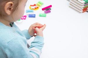 The girl at the table is playing with modeling dough. Childrens games for fine motor skills photo