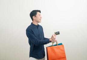 retrato, joven, asiático, hombre, tenencia, tarjeta de crédito, y, bolsa de compras foto