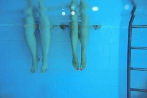 two people legs underwater in the swimming pool. Party. Summer. Vacation, diversity, friendship and sport concept. photo